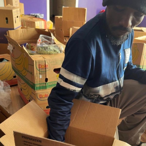Man packing boxes in a room filled with banana boxes.