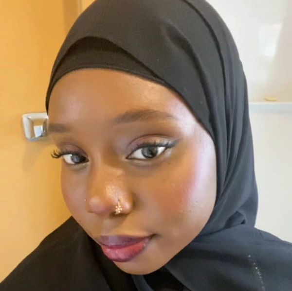 Close-up of a woman wearing a black hijab and nose jewelry.