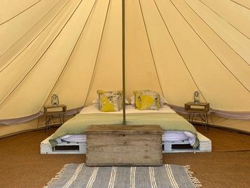 Cozy bed setup inside a canvas tent with rustic decor.