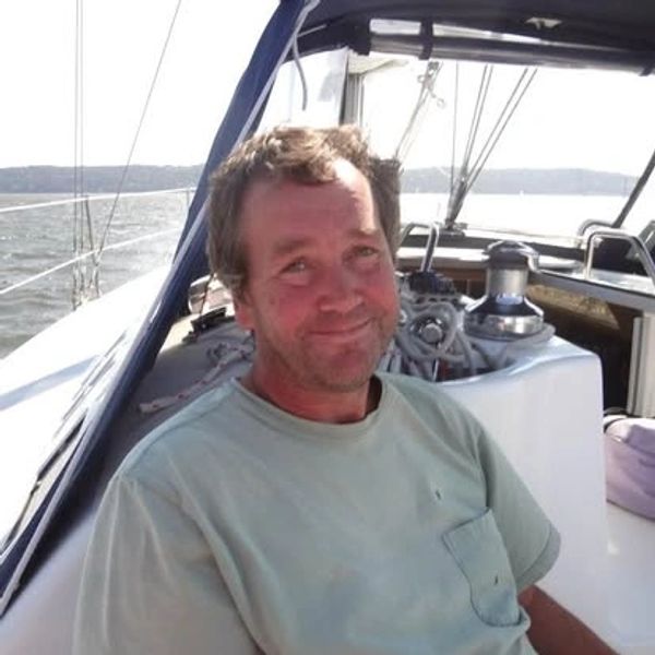 Man smiling on a boat under a canopy.