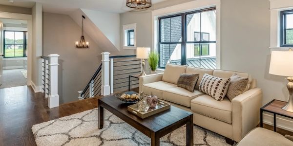 Clean interior of home. Living room with couch, coffee table and stairs leading down to main floor