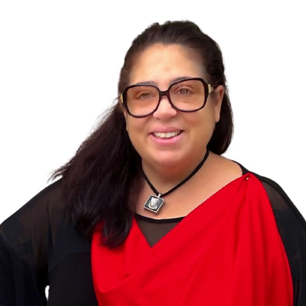 Smiling woman wearing large glasses, a red and black outfit, and a pendant necklace.