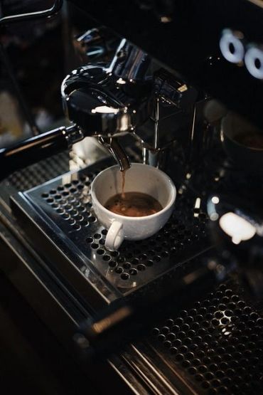 Espresso pouring into a white cup from a coffee machine.