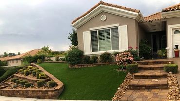 Well-manicured front yard with stone steps and green lawn.