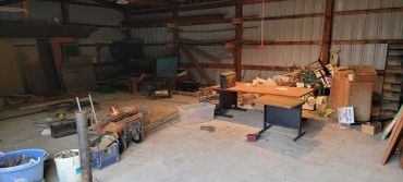 A cluttered workshop or garage with various tools and materials scattered around.