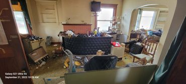 Cluttered and messy living room with old furniture and scattered items.
