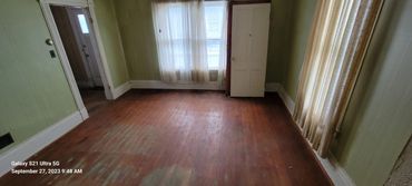 Empty room with worn wooden floor and green walls.