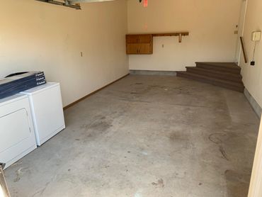 Empty garage with washer, dryer, and wall cabinet.