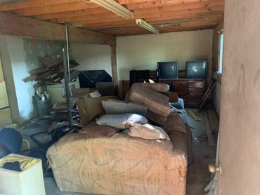 Cluttered basement with old furniture and two vintage TVs.