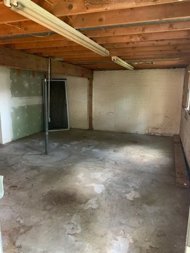 Empty basement with exposed ceiling and stained concrete floor.