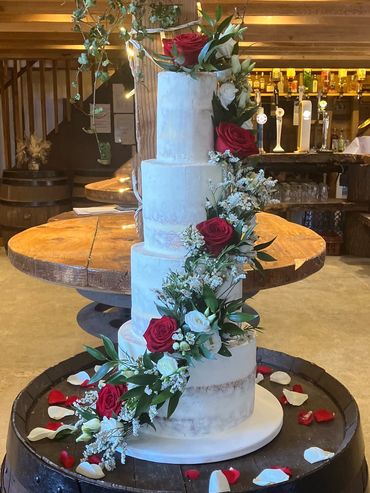 Semi-Naked wedding cake with cascade of red roses and white flowers