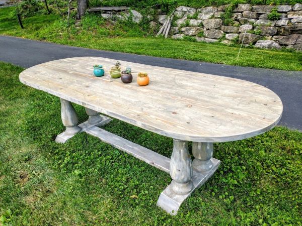 Wooden oval outdoor table with small plants.