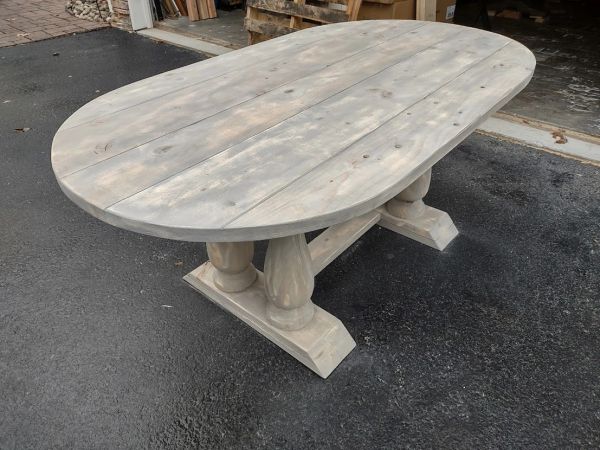 Rustic oval wooden dining table with sturdy pedestal base.