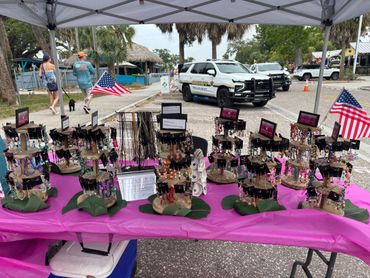 Handmade jewelry displayed at an outdoor market with sheriff vehicles in the background.