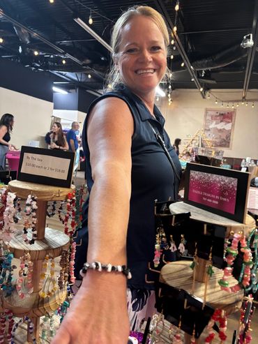 Smiling woman reaching out with bracelet display in foreground.