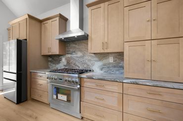 Custom kitchen design with stainless steel appliance, range hood, granite countertops and backsplash