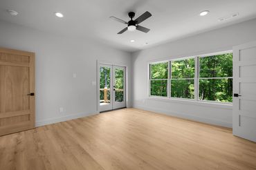Color drenched master bedroom with large window views of the wooded areas and custom white oak doors