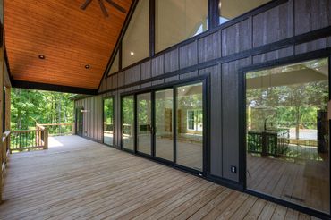 View of giant windows and oversized sliding glass door with stained tongue & groove and wood deck