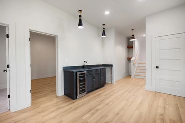 View of the custom wet bar, custom lighting, and blond LVP flooring in the terrace level