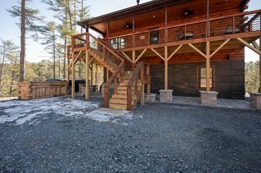 Side view of a custom built log cabin with covered wood upper deck and lower concrete patio