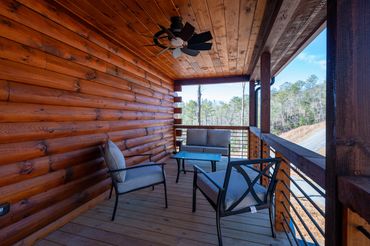 Outside sitting area at a custom log cabin with stained log siding and custom black ceiling fan
