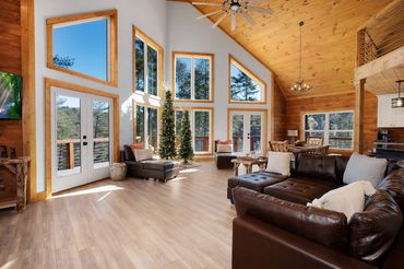 Brown couch with wood shiplap and tongue & groove ceiling with a wall of windows and glass doors