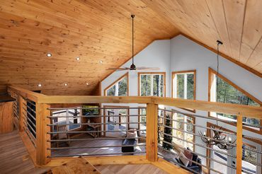 Stained pine tongue & groove ceiling with rustic wood & painted rebar railing and a wall of windows