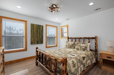 Amish build wood bed and side table in a guest bedroom with LVP flooring and wood trimmed windows