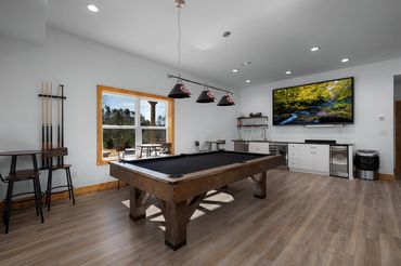 Pool table in the basement game room in a custom built log cabin with UGA lighting and big TV