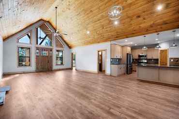 Open concept great room with stained tongue & groove ceiling with view of large kitchen and bar