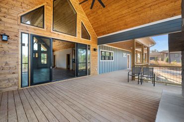 Vaulted wall of windows with 4 panel black metal and glass slider and trapezoid windows above