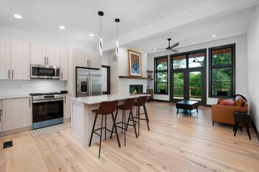 View of a modern open concept house from the front door with an island and back wall of windows