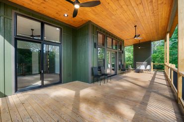 Covered back porch with stained tongue and groove ceiling wood burning fireplace & wall of windows