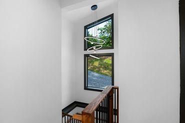 Custom railing in a modern style staircase with big angled windows and modern circular lighting