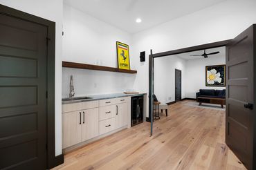 Large open room with blond hardwood floors and a wet bar & second room divided by double doors