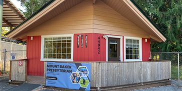 Small red ministry building with a Mount Baker Presbyterian banner.