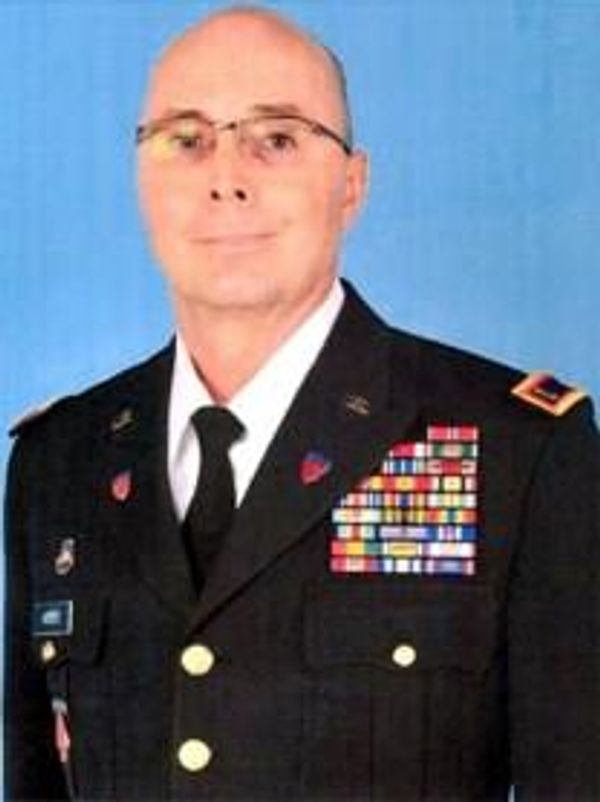 Military officer in uniform with many medals and a blue background.