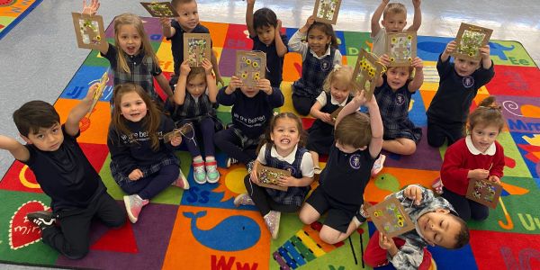 Happy children showing craft projects in a colorful classroom.