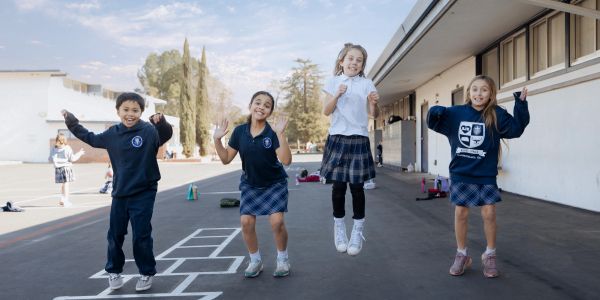 Children joyfully playing hopscotch at school recess.