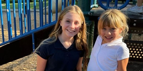 Two young girls smiling at a playground.