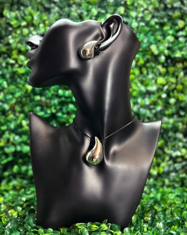Black mannequin bust displays matching silver teardrop-shaped earring and necklace.