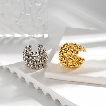 Two elegant, beaded open cuff rings in silver and gold on white surfaces.