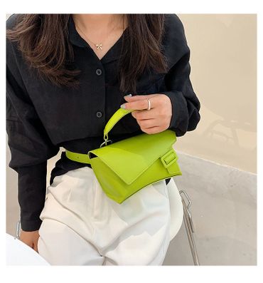 Woman in black blouse holding a bright green handbag.