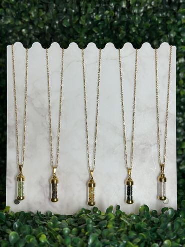 Five gold chain necklaces with cylindrical pendants containing colored stones.