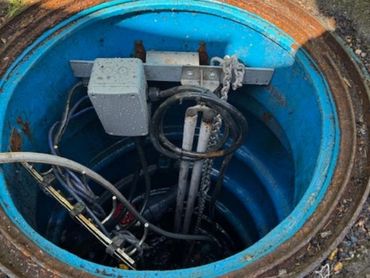 Open utility manhole with cables and equipment inside.