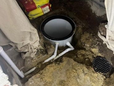 Basement plumbing installation with exposed pipes and cement bags.