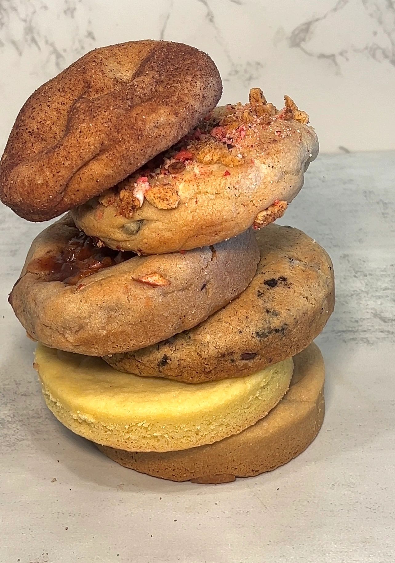 Stack of assorted freshly baked cookies with different textures and flavors.