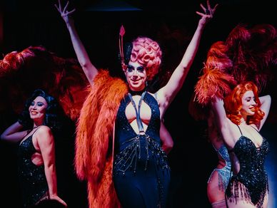 Performers in glamorous costumes on stage.