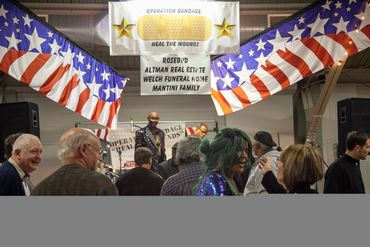 People gather under patriotic decorations at an event called Operation Bandage: Heal the Wounds.