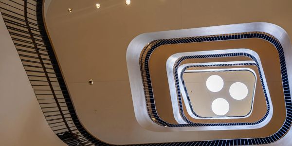 View looking up a spiral staircase with round lights.